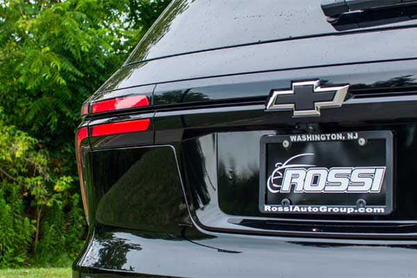 The back Rossi dealership license plate of a black GMC Traverse