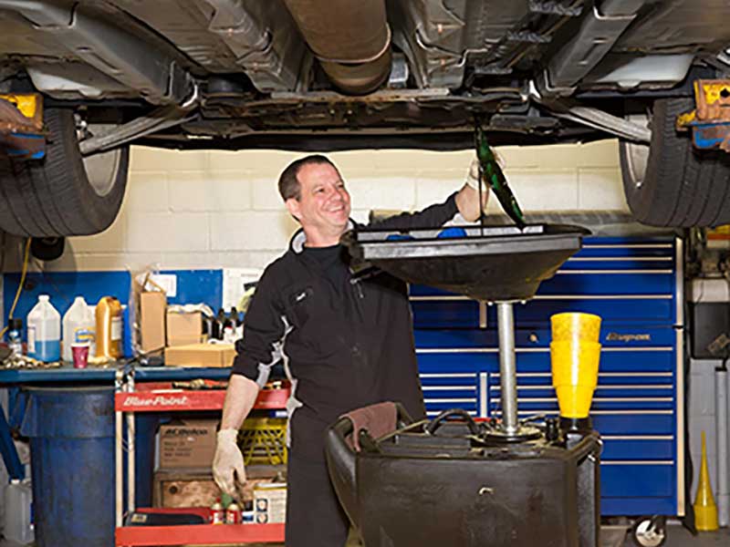 A service tech doing an oil change a car