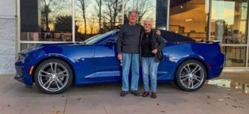 A happy couple who purchased a blue Camaro from Rossi Chevrolet GMC